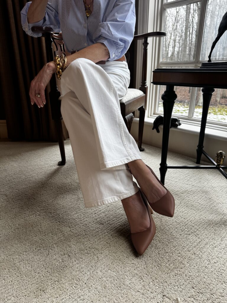 Ally Shoes Woman sitting wearing white pants and Ally Shoes heels